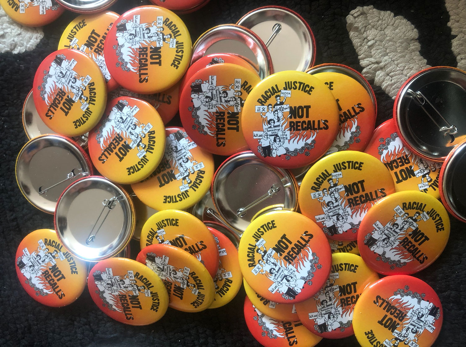Scattered buttons with the words "Racial Justice Not Recalls"